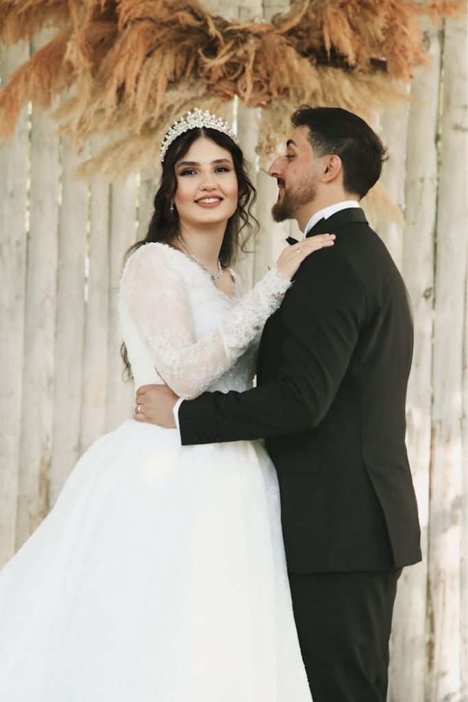 A charming couple posed in wedding attire with rustic background.