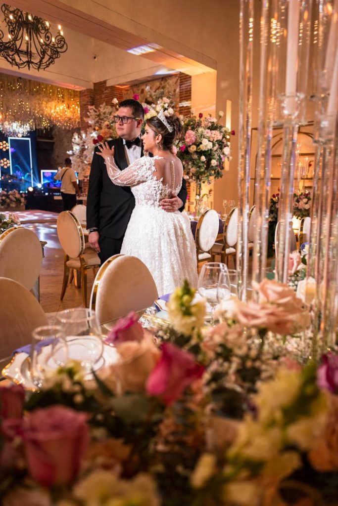Newlyweds embrace amidst floral decor at an elegant wedding reception.
