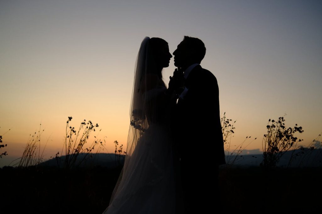 Romantic silhouette of a bride and groom against a golden sunset, capturing timeless love.